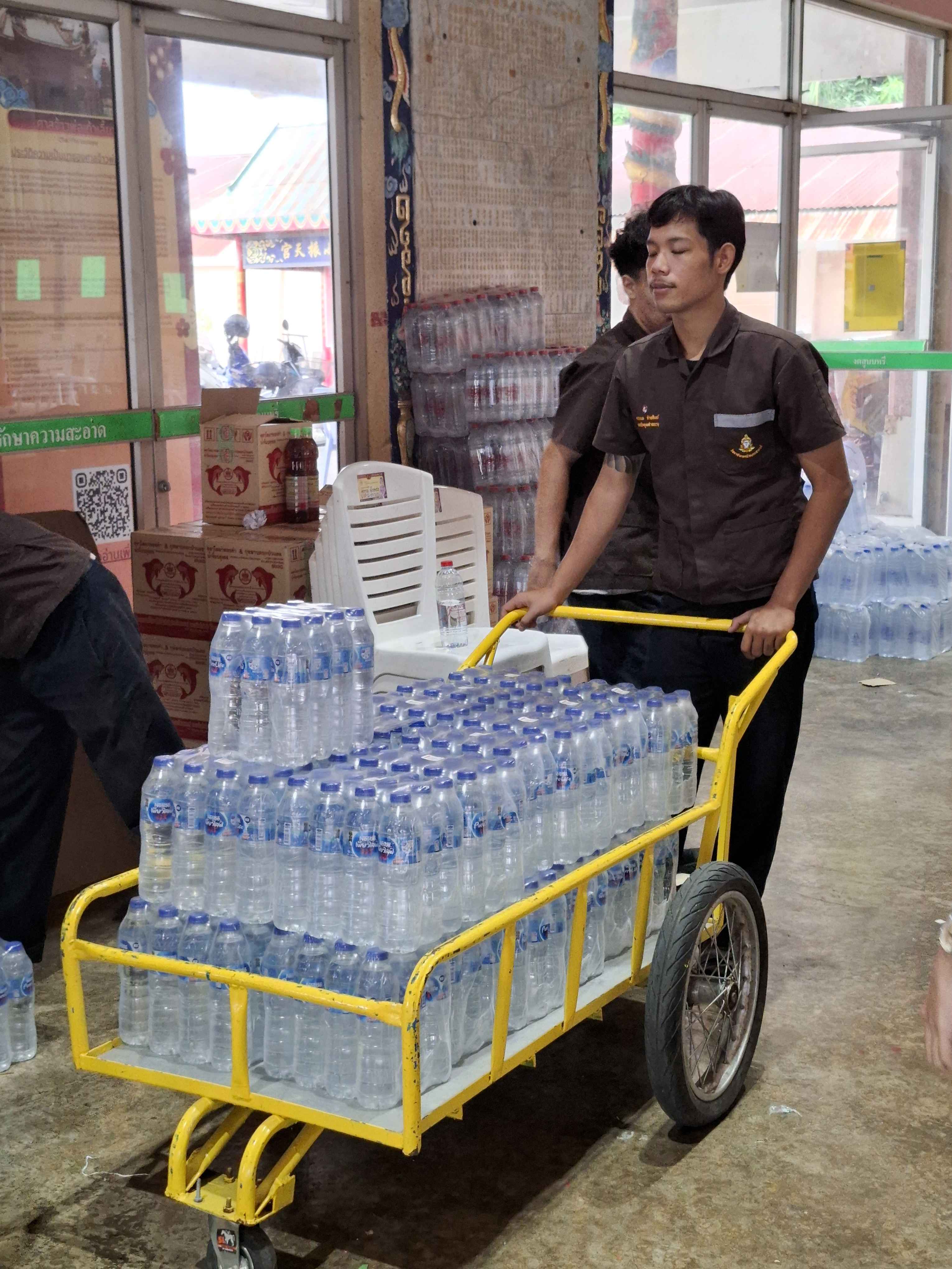 นักศึกษาเข็นรถเข็นขนน้ำดื่มบรรจุขวดเข้าสู่พื้นที่จัดงาน