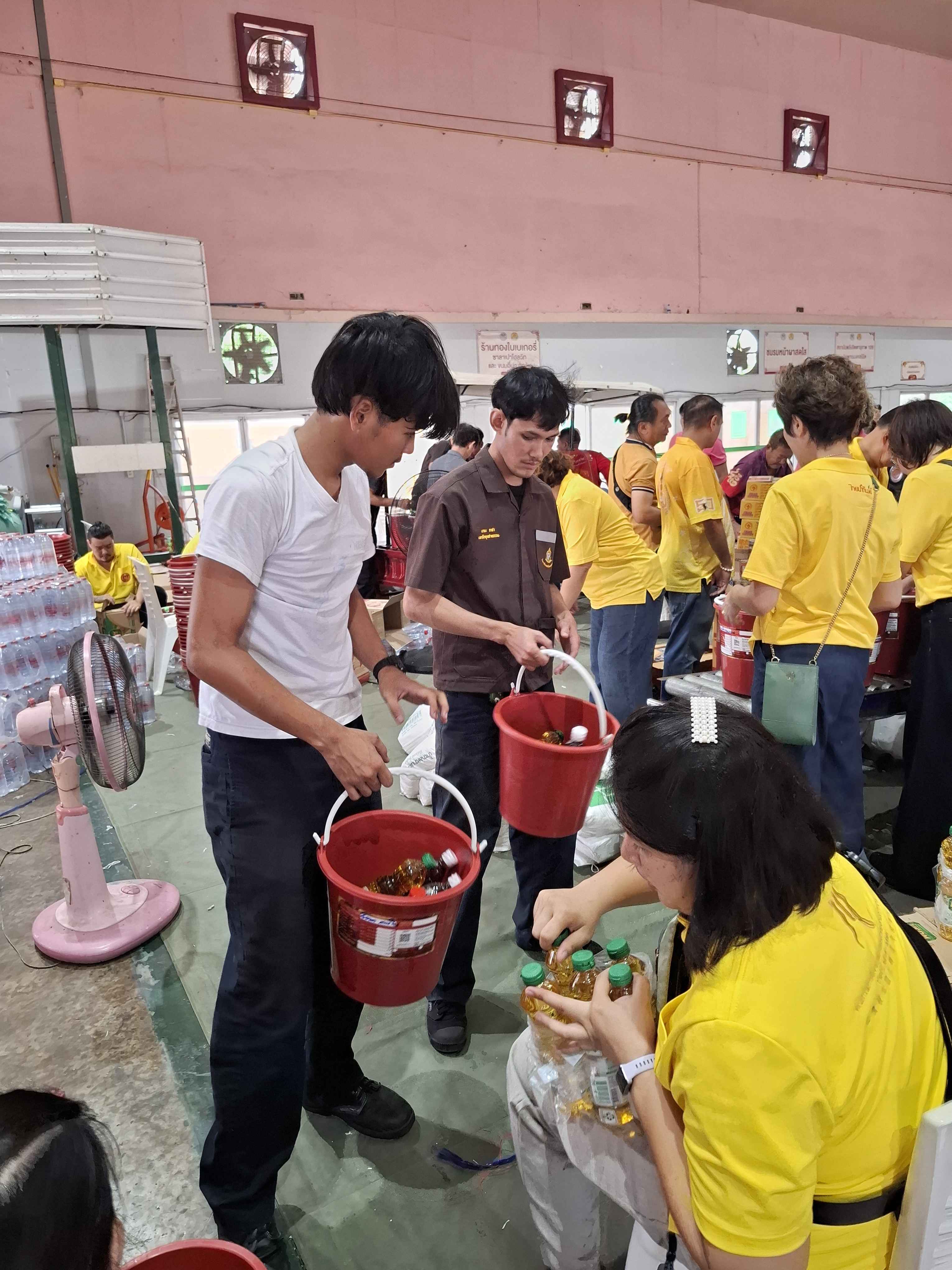 กลุ่มอาสาสมัครและนักศึกษาช่วยกันยกถังสังฆทานที่บรรจุสิ่งของเรียบร้อยแล้ว