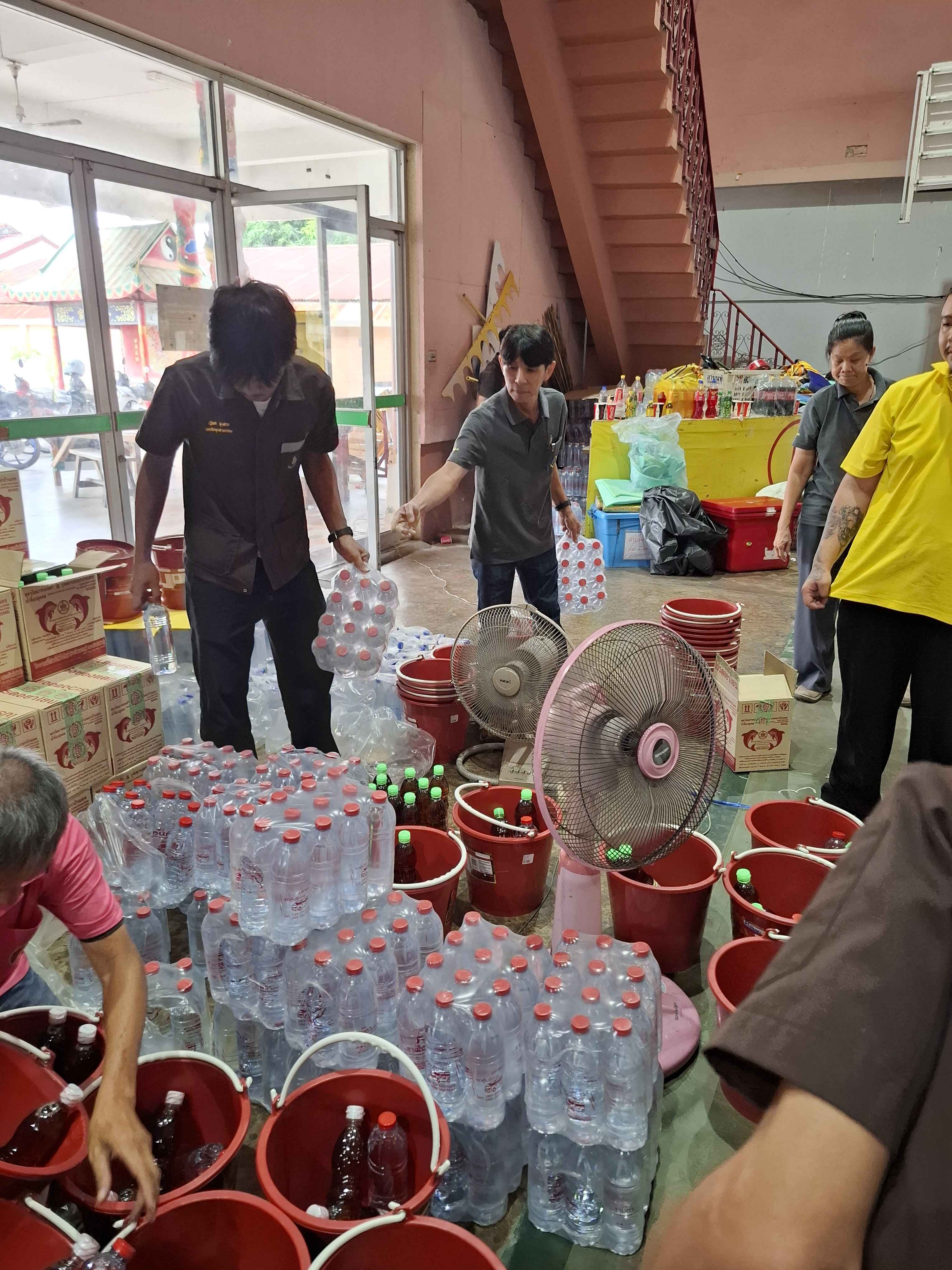 คณะทำงานช่วยขนย้ายน้ำดื่มบรรจุขวดและสิ่งของบริจาคอื่น ๆ ภายในอาคาร